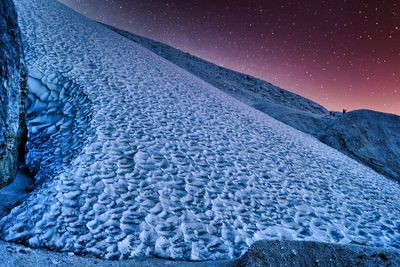 Scenic view of snowcapped mountains against sky at night