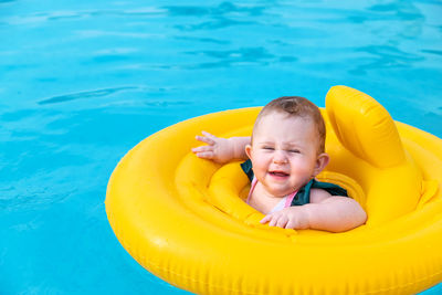 Cute girl with inflatable ring swimming in pool