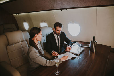 Businessman and secretary sitting in corporate jet