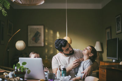 Father with children taking advice on video call through laptop at home during covid-19