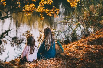 Rear view of women sitting on footpath during autumn