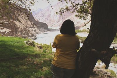 Rear view of woman standing by tree against sky