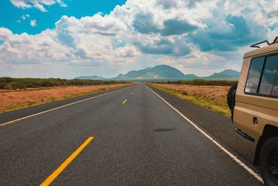 A safari vehicle on an empty highway against a mountain background at marsabit county, kenya