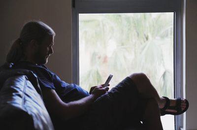 Man using mobile phone on sofa at home