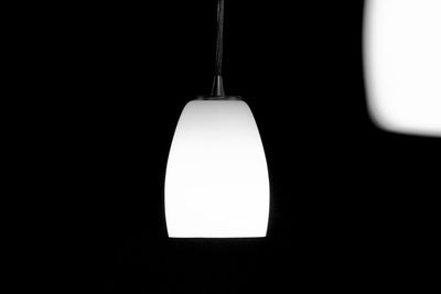 Close-up of light bulb hanging against black background