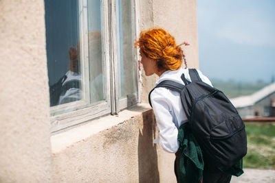 Rear view of woman standing against white wall