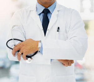 Midsection of doctor holding stethoscope