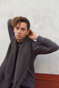 Portrait of young man standing against wall