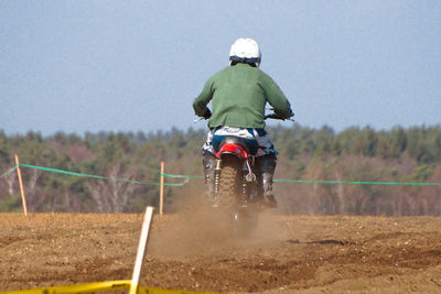 Rear view of man riding motorcycle on field