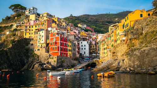 Buildings by river against sky in city