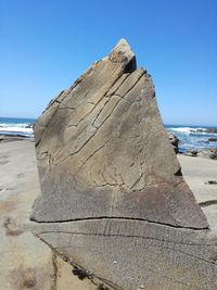 Rock formation on beach against clear blue sky