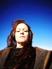 Low angle view of woman standing against clear blue sky