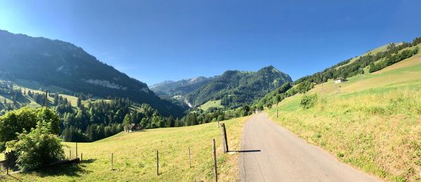 Road amidst green landscape and mountains against sky