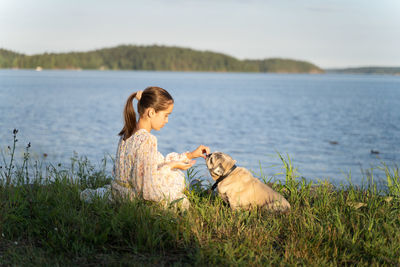A girl and a pug on the lake shore
