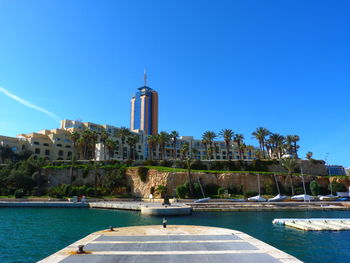 View of swimming pool by building against blue sky