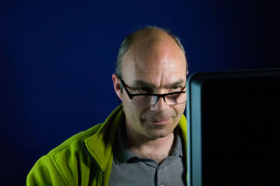 Smiling man using computer against wall at home