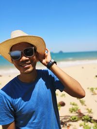 Portrait of mature man wearing sunglasses at beach against sky