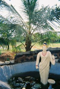 Portrait of young woman standing by palm tree