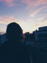 Rear view of silhouette woman standing against sky during sunset