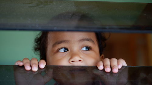 Close-up of cute boy looking through window