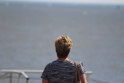 Rear view of man looking at sea against sky