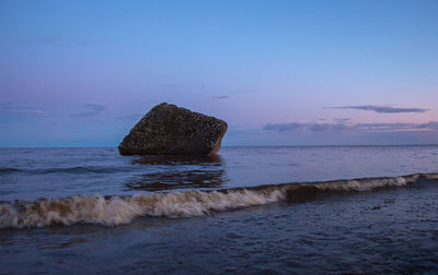 Scenic view of rocks on beach against sky during sunset