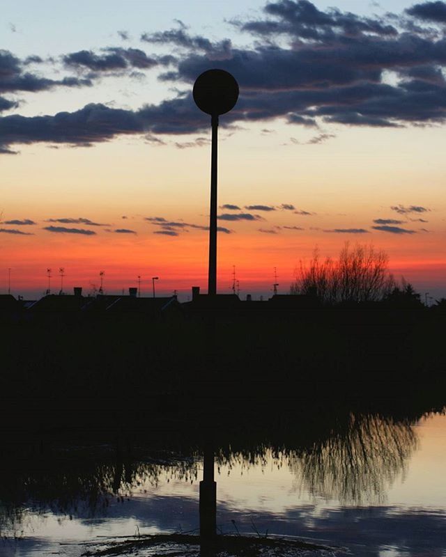 sunset, silhouette, sky, water, tranquility, scenics, tranquil scene, orange color, beauty in nature, cloud - sky, reflection, street light, idyllic, nature, sea, dusk, cloud, lake, lighting equipment, dramatic sky