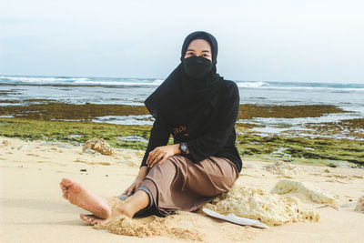 Portrait of young woman sitting at beach