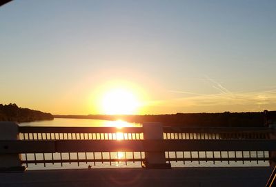 Silhouette bridge in front of calm lake at sunset