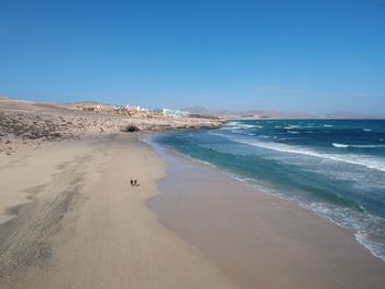 Scenic view of beach against clear blue sky