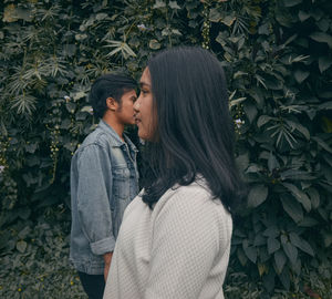 A man and a woman as if kissing against the background of leaves