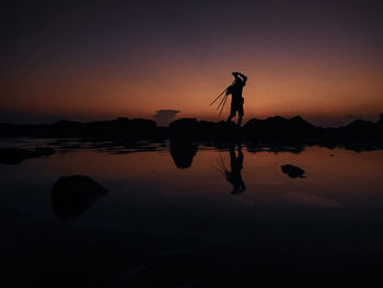 Silhouette man standing on beach against sky during sunset