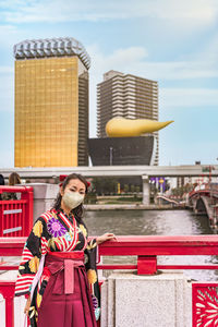 Japanese woman wearing a face mask in hakama kimono in front of olympic golden flame in asakusa.