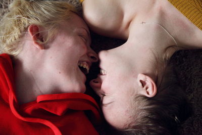 Close-up of smiling lesbian couple face to face on rug at home