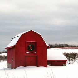 Red house on snow covered building against sky