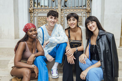 Smiling man with friends on staircase in front of door