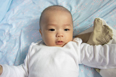 Portrait of cute baby lying on bed