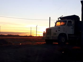 Vehicles on road against sky during sunset