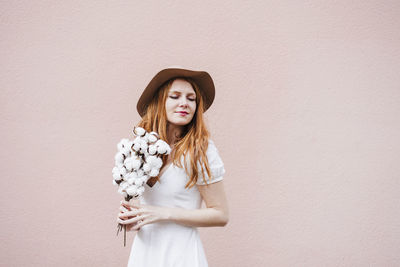 Portrait of young woman standing against wall