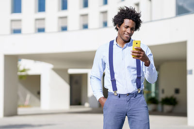 Young man using mobile phone while standing outdoors