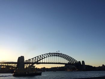 Sydney harbor bridge over sea against sky during sunset