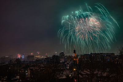 Firework display in city against sky at night