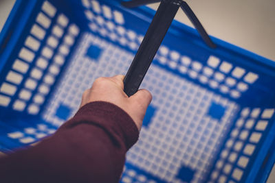 Close-up of hand holding blue basket