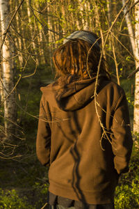 Rear view of woman walking against trees at forest