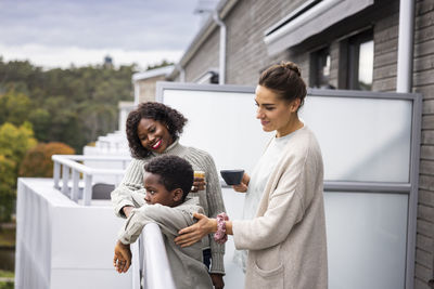 Female couple with son relaxing on balcony