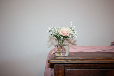 Close-up of flower vase on table against wall