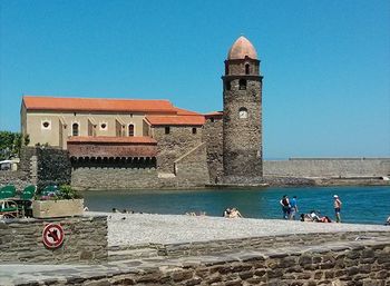 People by sea against clear blue sky