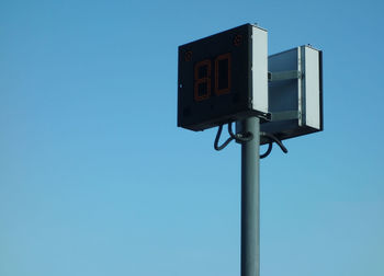 Low angle view of telephone pole against clear blue sky