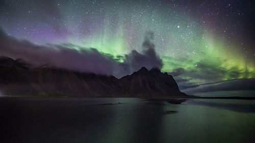 Scenic view of sea against sky with aurora borealis at night at vestrahorn, iceland