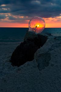 Close-up of rock on beach against sky during sunset